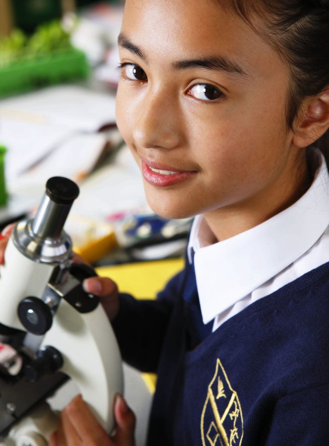 Portrait of teenage girl in school science lesson with microscope, visual brand library photography