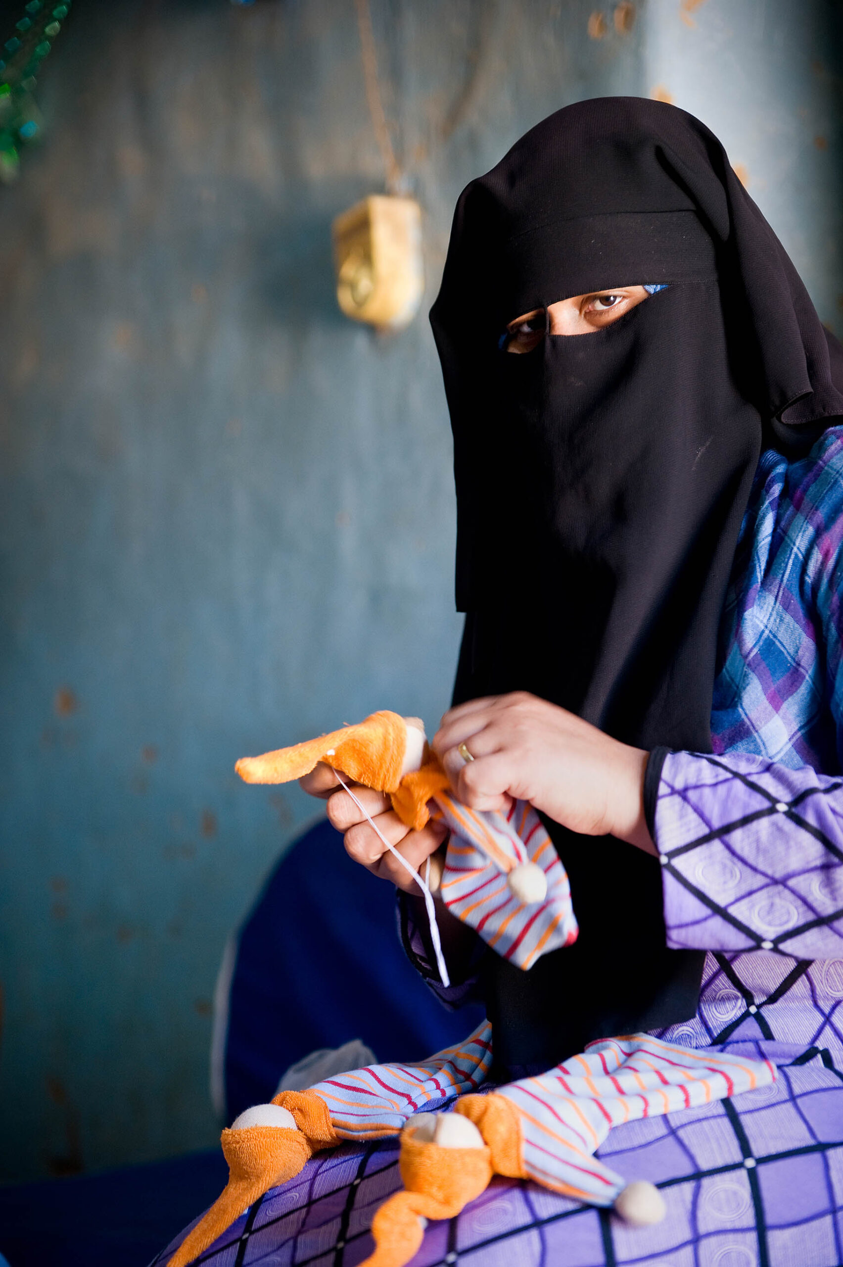 A woman in black niqab holding an orange.