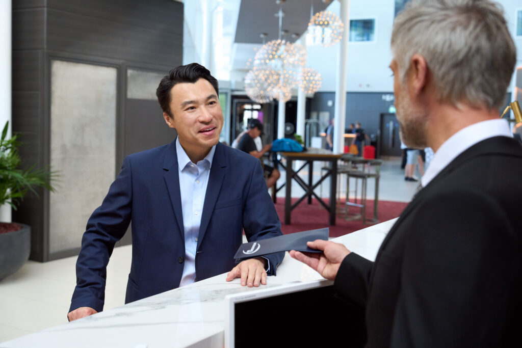 Global Multi-Location Photography. Professional male traveller checks into the hotel concierge