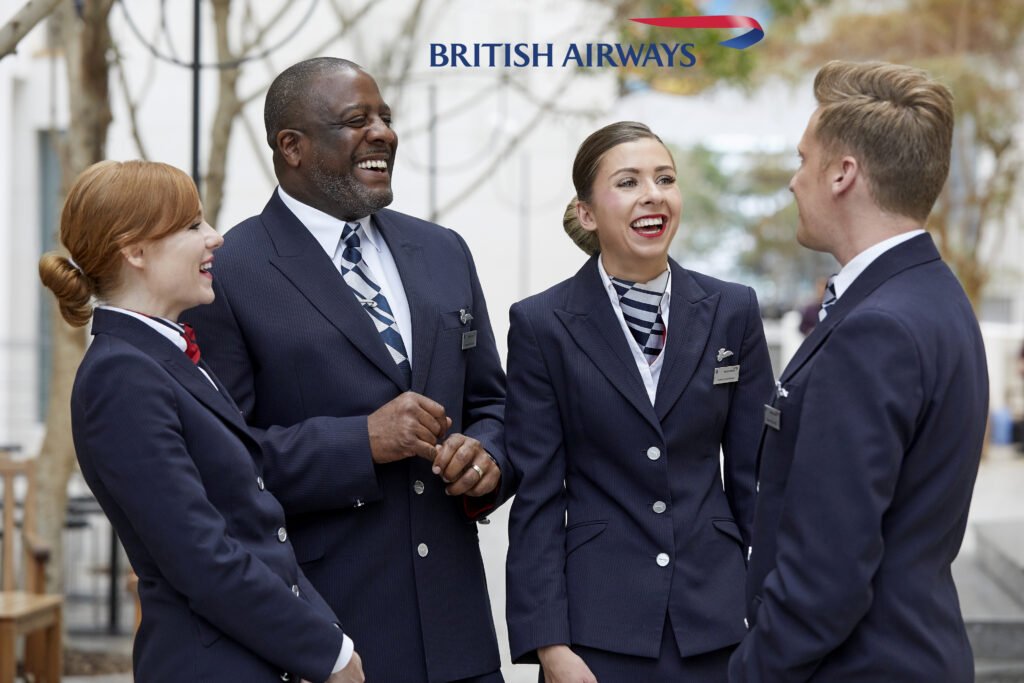 Group ethic group of air British Airway stewards in uniform laughing together.