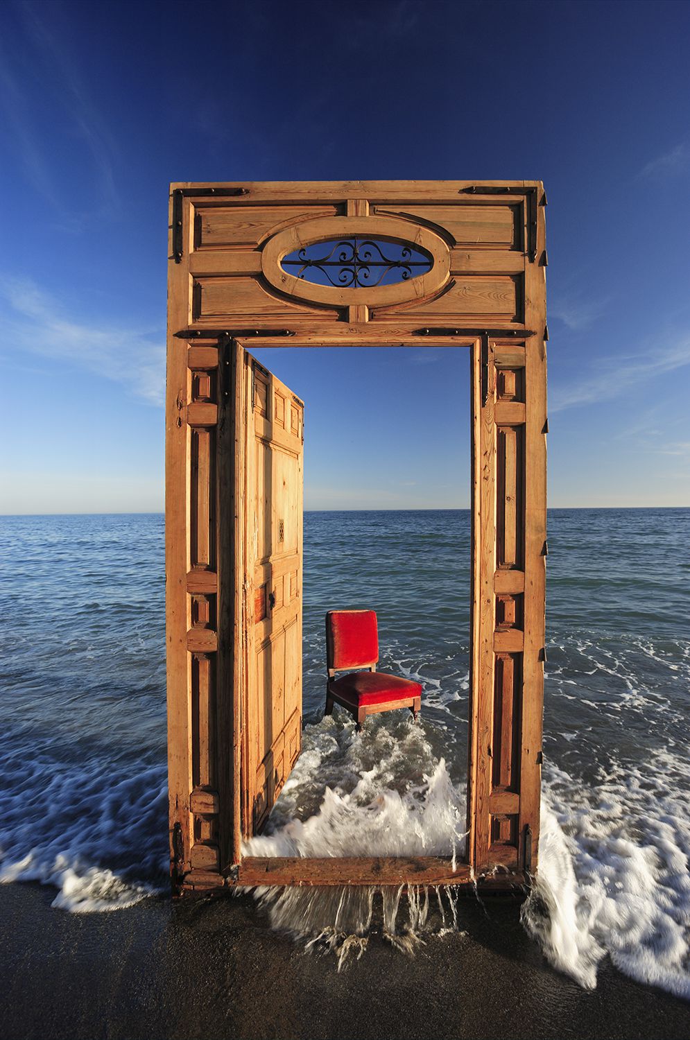 Wayne Chasan Hospitality, Architecture, Hotel Resorts, Lifestyle, Landscape, Editorial,  Environmental CSR Social Enterprise Lifestyle Photographer Photography Local, Regional, Global Hotel Resort, Holiday, Luxury, Front Cover Magazine creative image of wooden door frame in the sea with a red chair