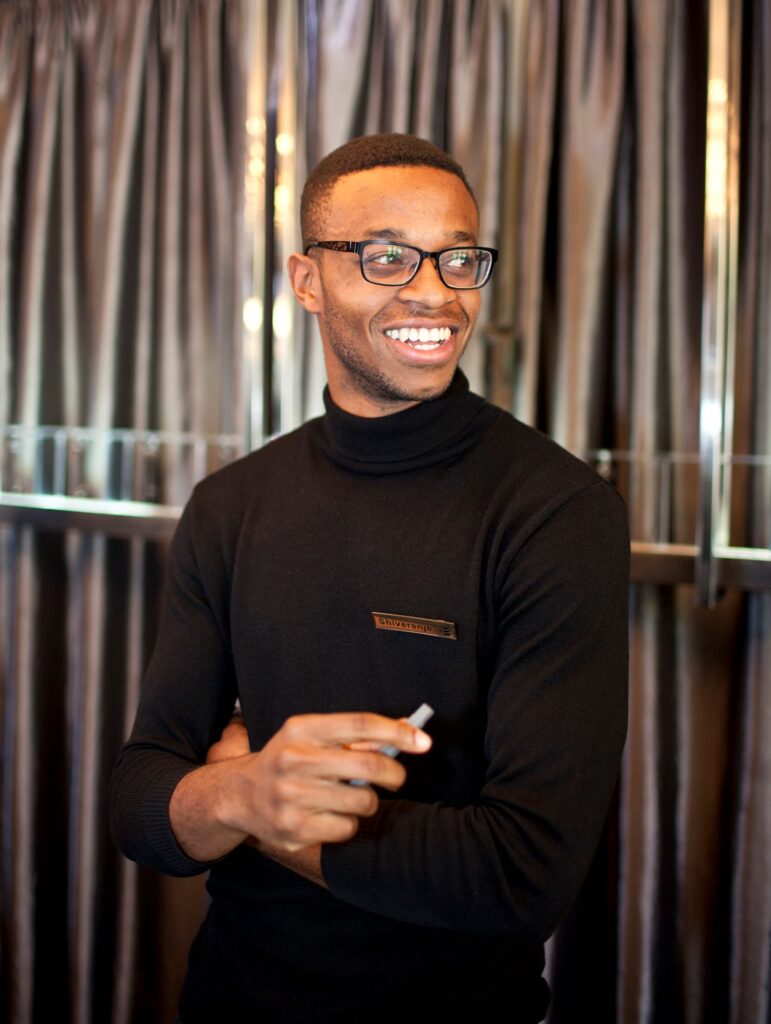 A man in black shirt holding a cigarette.