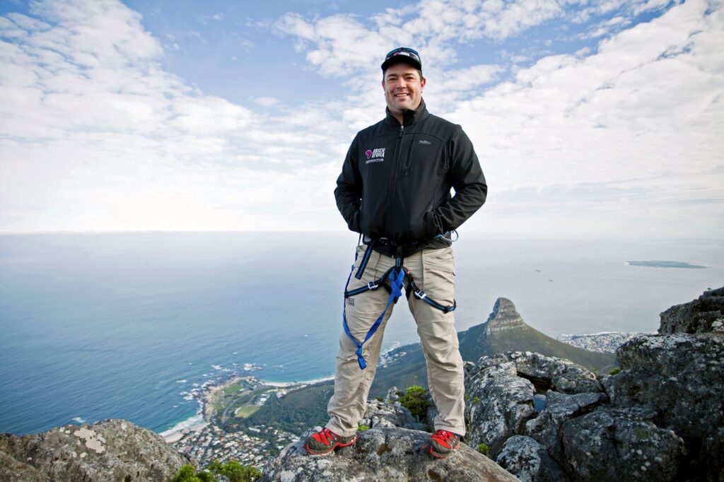 Commercial Brand Photography A man standing on top of a mountain with a rope.