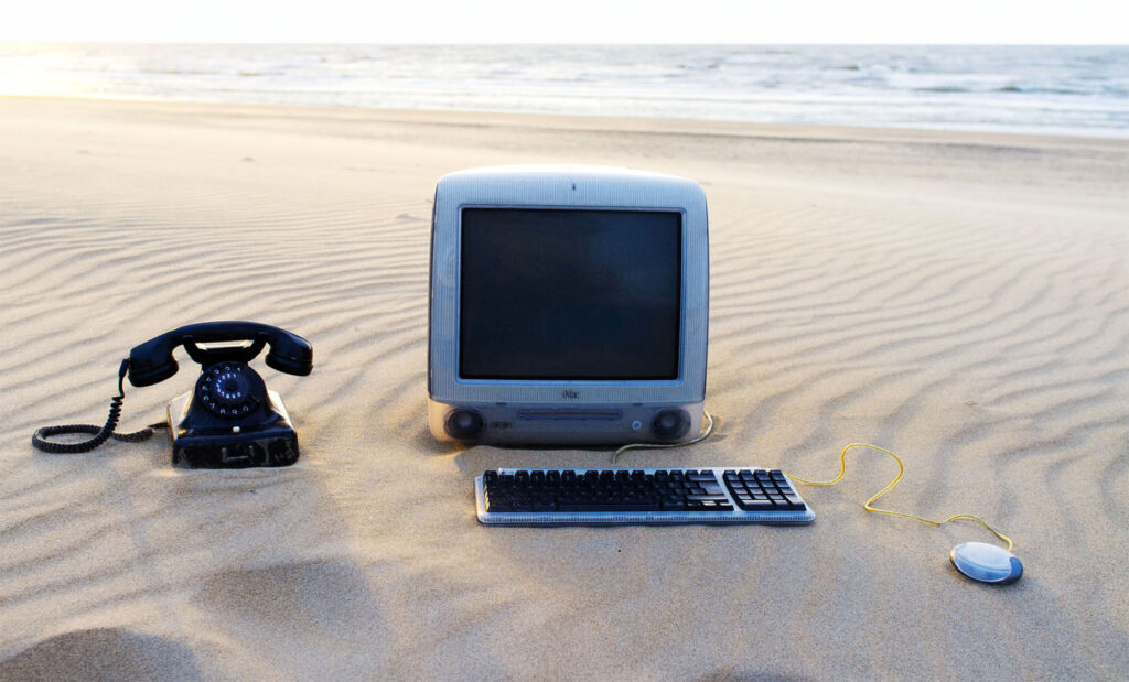 Global Assignments agency photographer Michel Porro Netherlands Europe Amsterdam People Portrait Corporate Entertainment Photography Shared Values visual storytelling Fine Art Photography Old computer monitor telephone keyboard and mouse on deserted sandy beach sun glistening on the sea