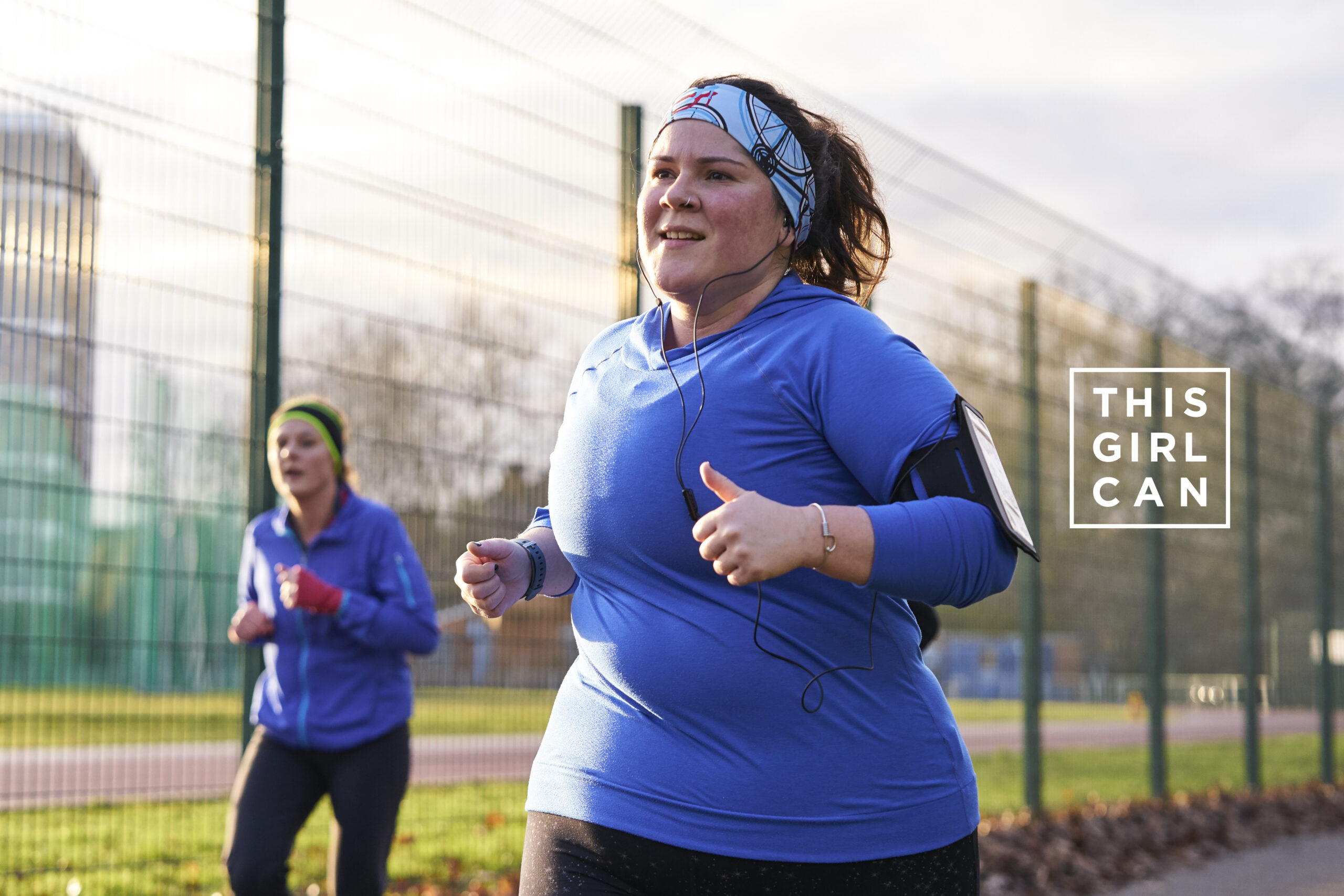 Global Assignments agency photographer Duncan Nicholls, London & UK. People, Portrait, Positive Lifestyle, Brand Library & Environmental Expertise Photography This Girl Can campaign Sports England Girl with blue bandana blue t-shirt and black leggings runs in the park at Park Run giving a thumbs up