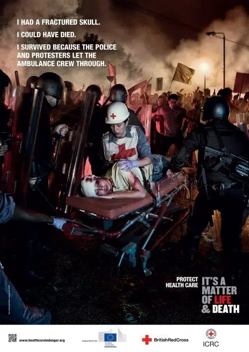 Medical workers carrying an injured person through a protest scene, staged for ICRC campaign on healthcare in conflict